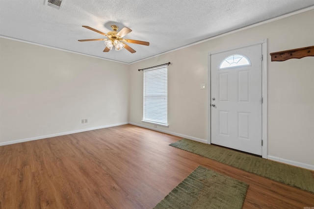 foyer entrance with baseboards, visible vents, a ceiling fan, wood finished floors, and a textured ceiling