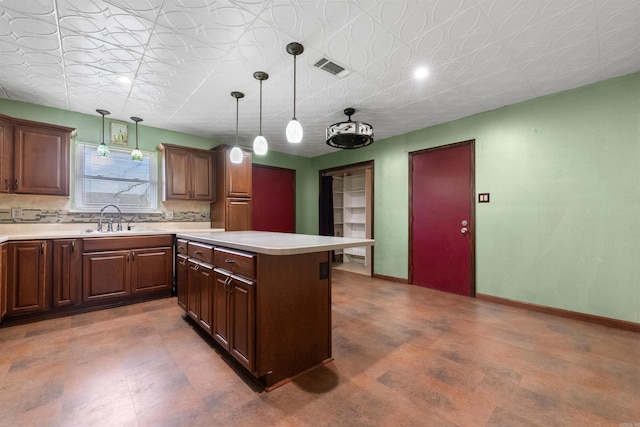 kitchen featuring a kitchen island, a sink, visible vents, and baseboards