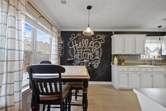 dining space featuring light tile patterned floors, baseboards, visible vents, and crown molding