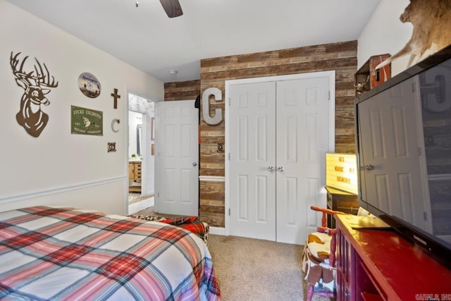 carpeted bedroom featuring a closet, ceiling fan, and wooden walls