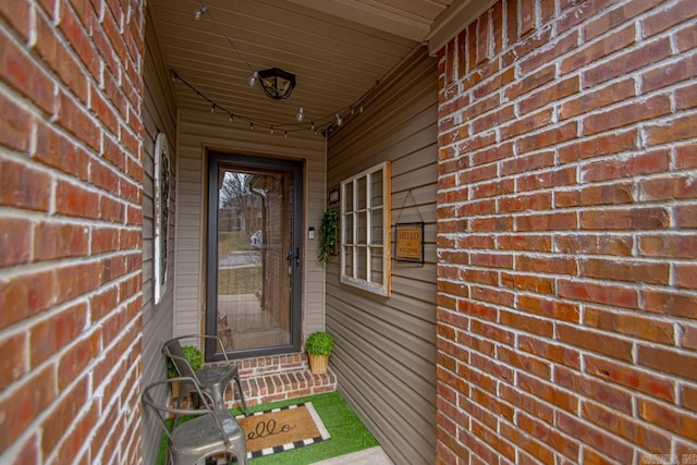 view of exterior entry featuring brick siding