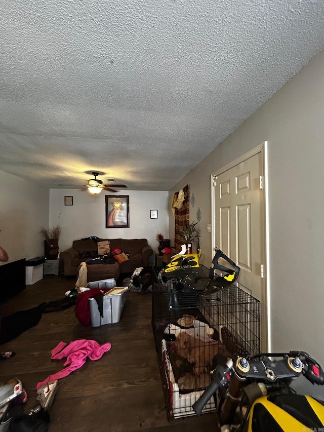 living room featuring a textured ceiling, a ceiling fan, and wood finished floors