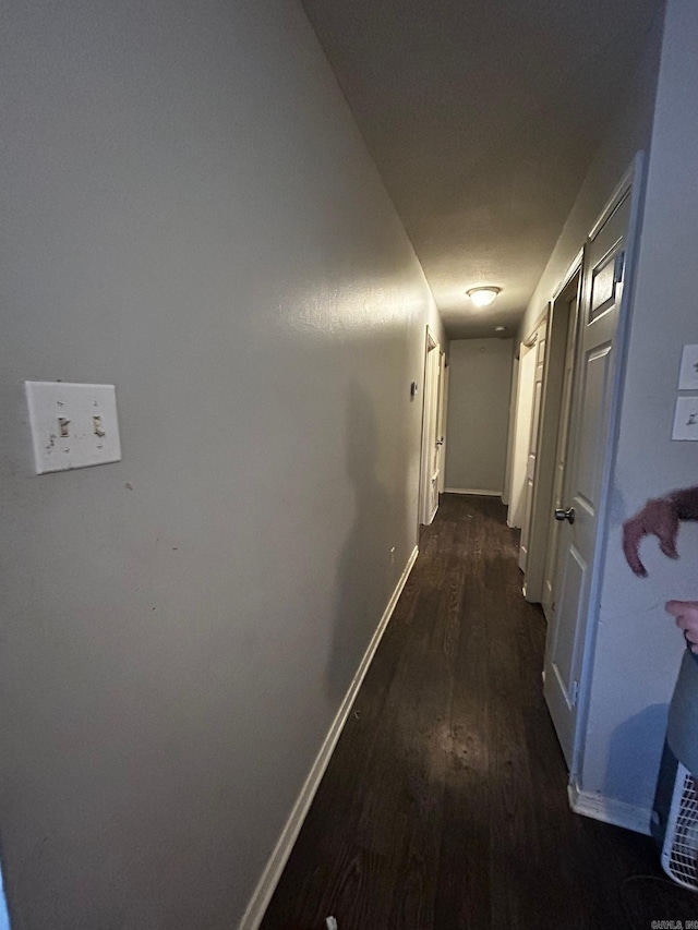 hallway with dark wood-style floors and baseboards