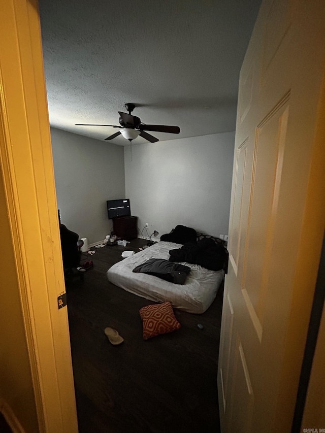 bedroom featuring ceiling fan, a textured ceiling, and wood finished floors