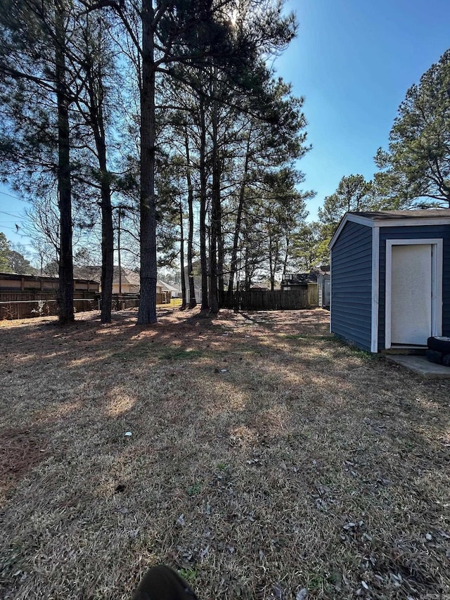 view of yard with fence, an outdoor structure, and a storage unit