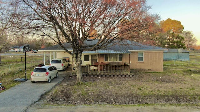 view of front of house featuring driveway, metal roof, crawl space, fence, and brick siding