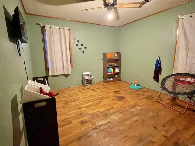 interior space featuring ornamental molding, wood finished floors, and a ceiling fan