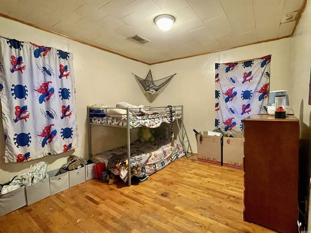 bedroom featuring crown molding, visible vents, and wood finished floors