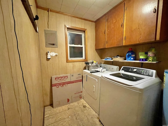 clothes washing area with cabinet space, electric panel, ornamental molding, wood walls, and washing machine and dryer