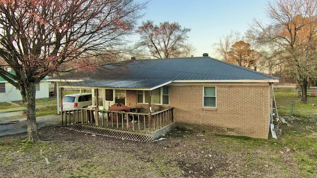 back of property with crawl space, a wooden deck, metal roof, and brick siding