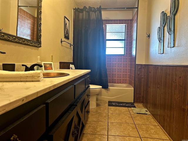 bathroom featuring toilet, a wainscoted wall, shower / tub combo, vanity, and tile patterned floors