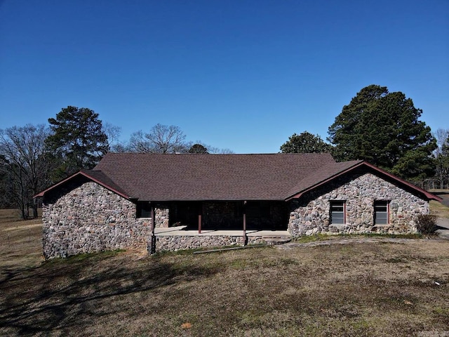 ranch-style house with stone siding, a front yard, and a patio