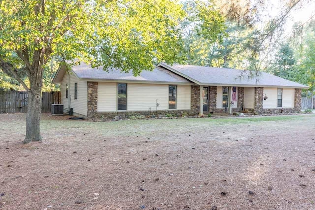 ranch-style home featuring central AC, stone siding, and fence