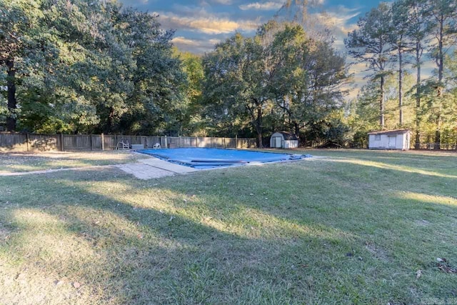 view of swimming pool with a fenced backyard, a storage shed, an outdoor structure, a lawn, and a fenced in pool