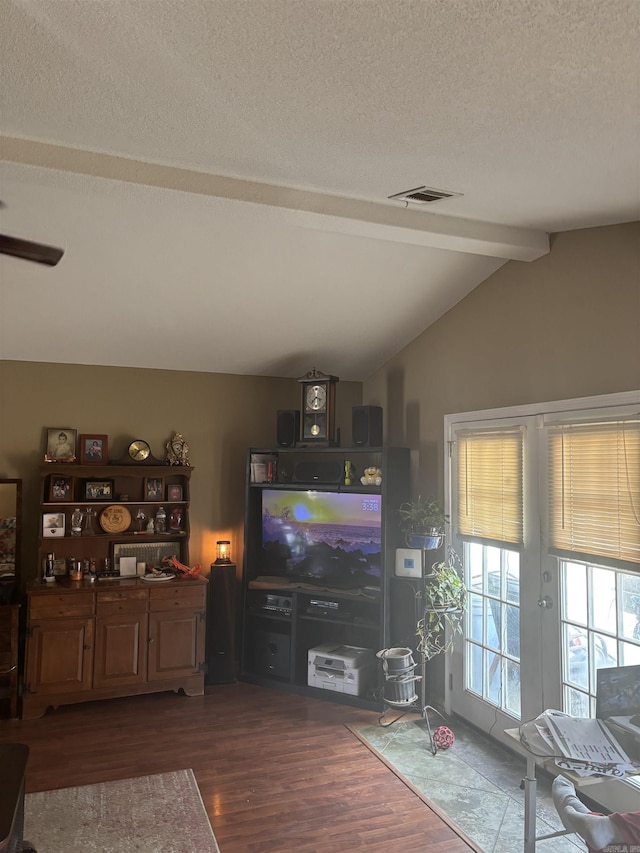 living room with visible vents, vaulted ceiling with beams, a textured ceiling, and wood finished floors