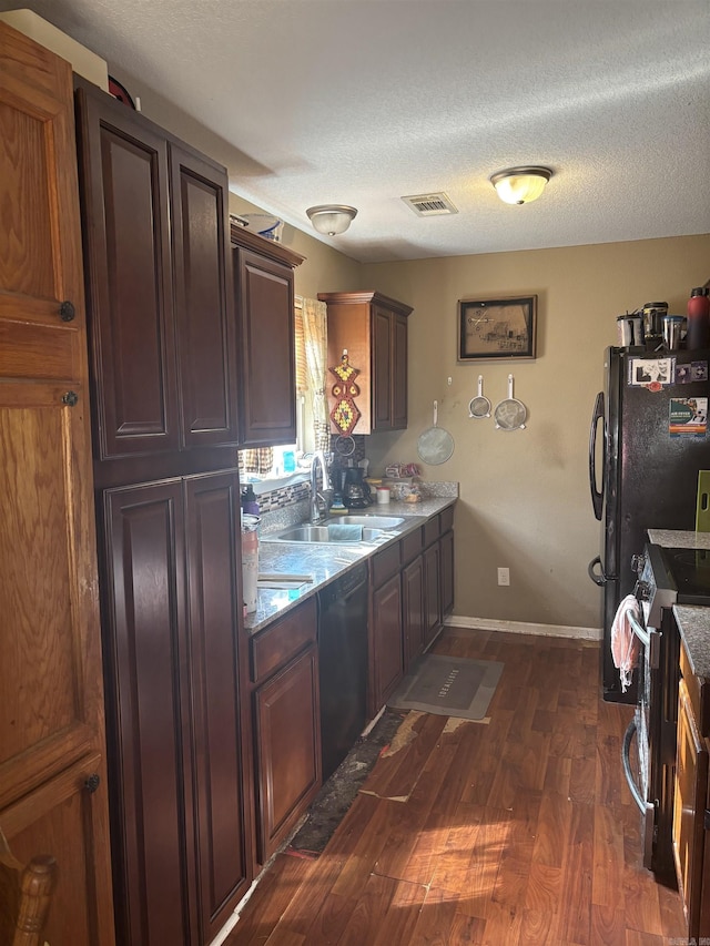 kitchen with a textured ceiling, a sink, visible vents, black appliances, and dark wood finished floors