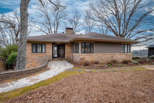 single story home featuring stone siding, a chimney, and roof with shingles