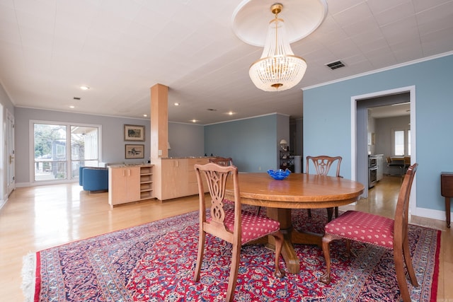 dining area featuring baseboards, visible vents, crown molding, light wood-type flooring, and a notable chandelier