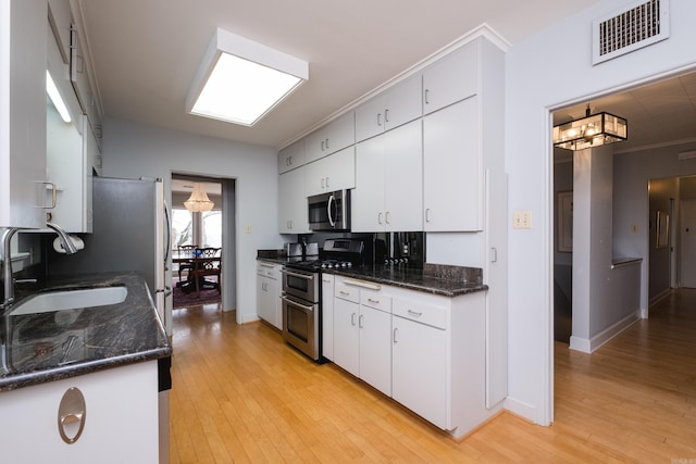 kitchen featuring light wood finished floors, visible vents, appliances with stainless steel finishes, and a sink