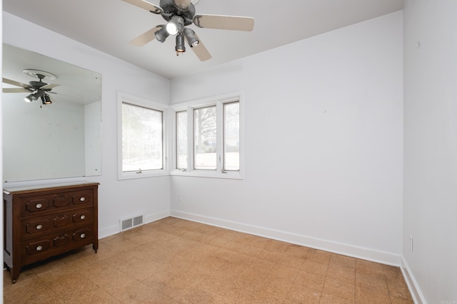 spare room with ceiling fan, light floors, visible vents, and baseboards