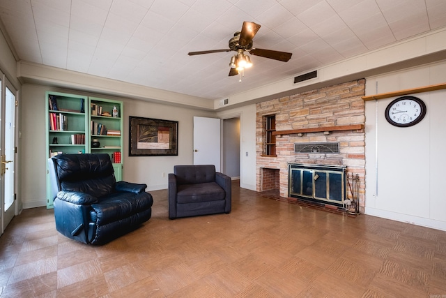 living room featuring a ceiling fan, a fireplace, visible vents, and baseboards