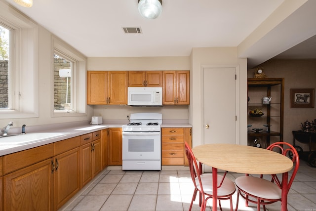 kitchen with light countertops, white appliances, a sink, and visible vents