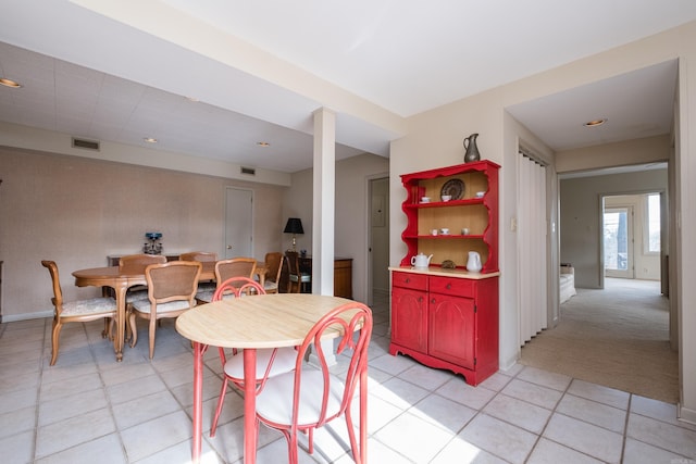 dining area featuring light tile patterned floors, baseboards, visible vents, and light colored carpet