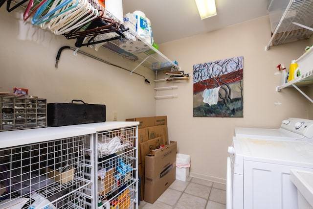 laundry room featuring light tile patterned flooring, laundry area, a sink, baseboards, and independent washer and dryer