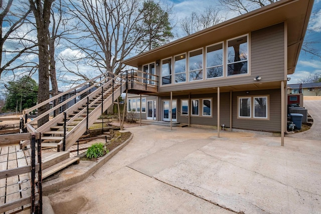 rear view of property featuring driveway and stairway