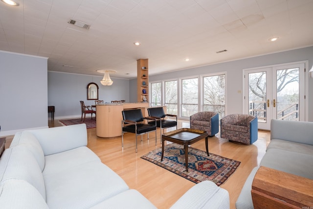 living room with light wood-type flooring, plenty of natural light, visible vents, and french doors