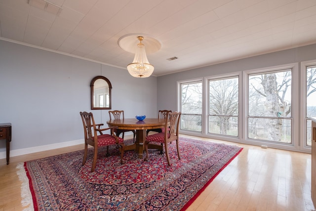 dining area with ornamental molding, wood finished floors, visible vents, and baseboards