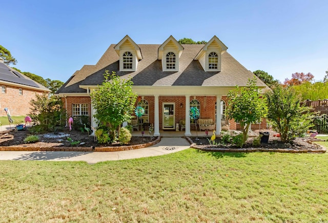 cape cod-style house featuring brick siding, a front lawn, and a shingled roof