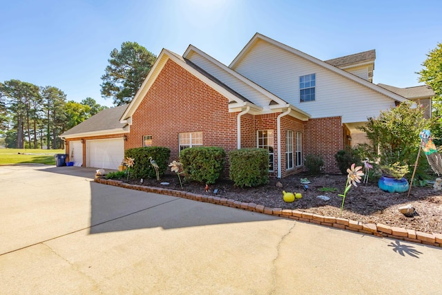 view of side of home with a garage, brick siding, and driveway