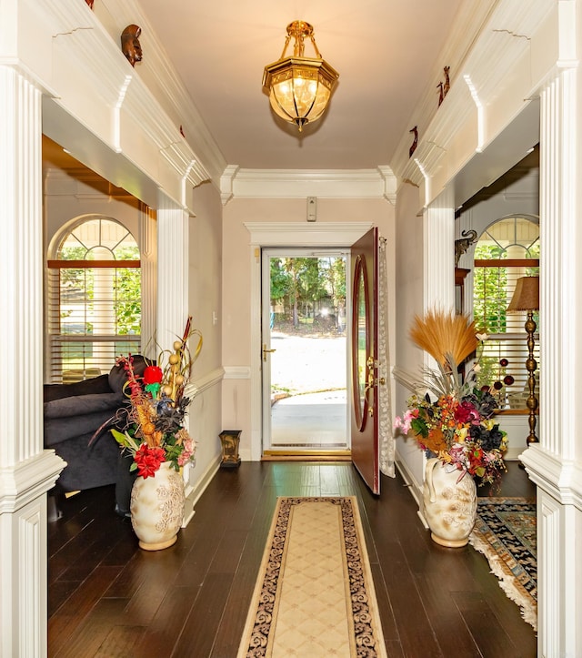 doorway to outside with crown molding, hardwood / wood-style flooring, baseboards, and ornate columns