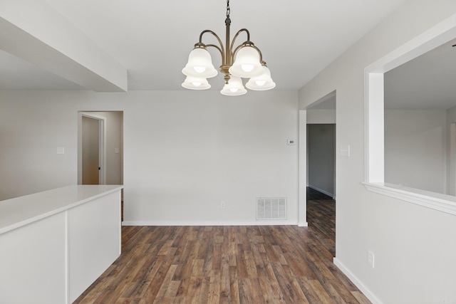 empty room with baseboards, dark wood finished floors, visible vents, and an inviting chandelier