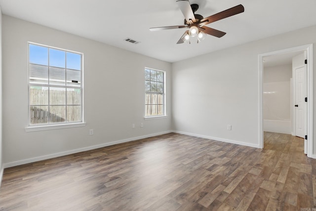 unfurnished room featuring ceiling fan, wood finished floors, visible vents, and baseboards