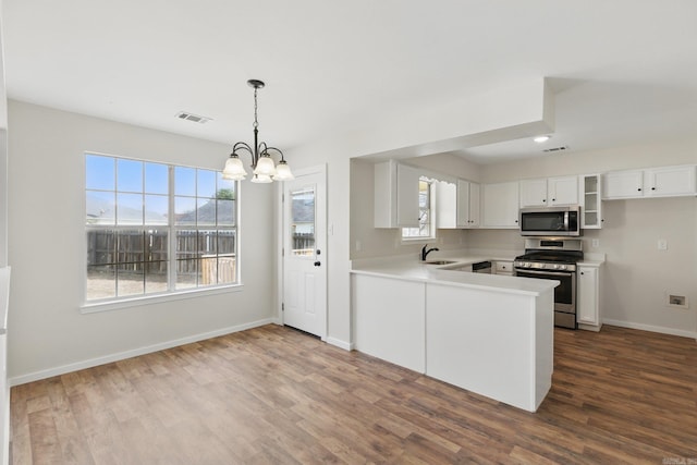 kitchen with dark wood finished floors, visible vents, appliances with stainless steel finishes, white cabinetry, and a sink