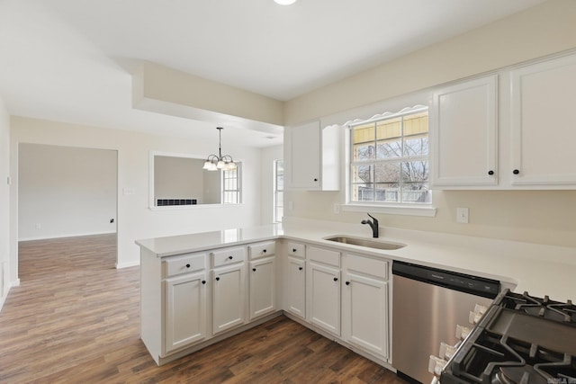 kitchen featuring dishwasher, a peninsula, white cabinetry, a sink, and gas stove