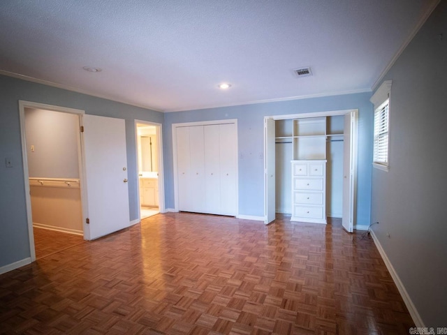 unfurnished bedroom featuring baseboards, ornamental molding, visible vents, and multiple closets