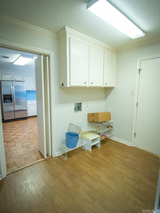 washroom featuring light wood-style floors, cabinet space, crown molding, and a textured ceiling