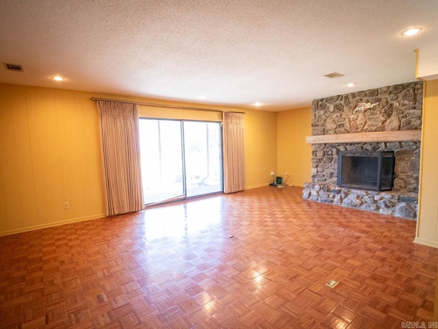 unfurnished living room featuring baseboards, a fireplace, visible vents, and a textured ceiling