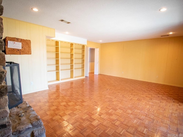 spare room with built in features, visible vents, a textured ceiling, and recessed lighting