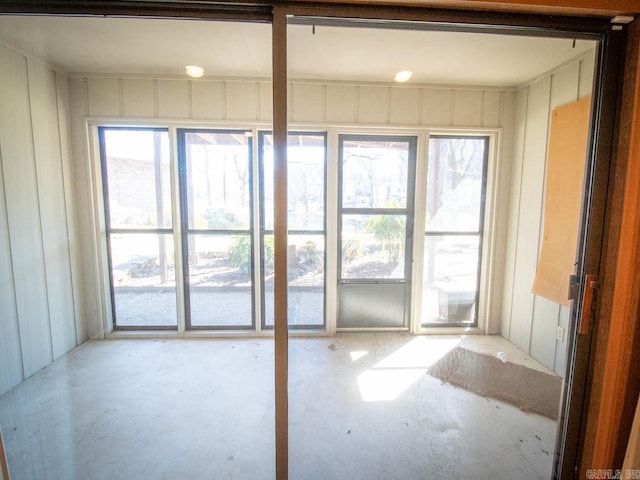 spare room featuring a sunroom, concrete floors, and a decorative wall