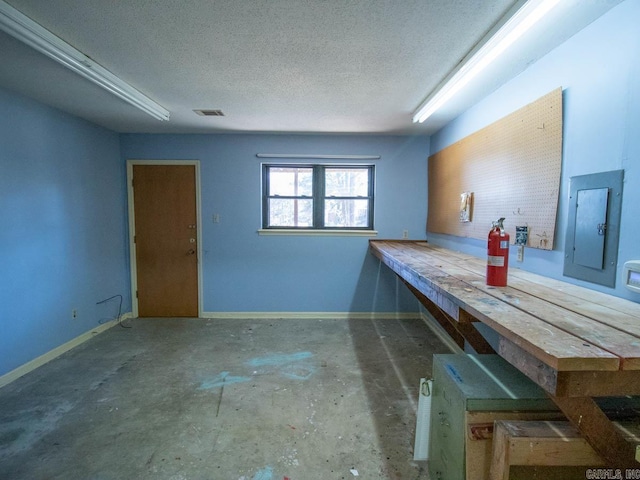 interior space with electric panel, visible vents, a textured ceiling, and baseboards