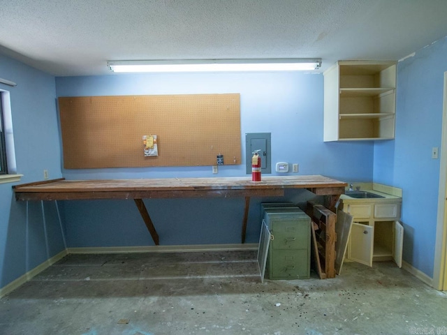 unfurnished office with a sink, a textured ceiling, and a workshop area