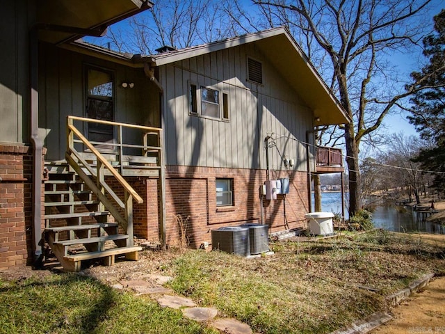 view of side of property with stairs, central AC unit, and brick siding