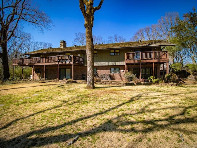 rear view of house featuring brick siding, a yard, a chimney, and a wooden deck