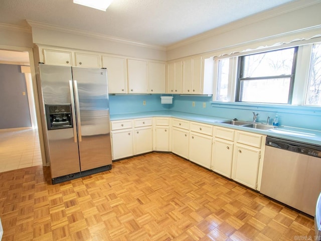 kitchen with stainless steel appliances, light countertops, a sink, and crown molding