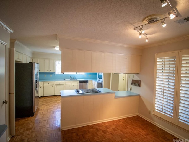 kitchen featuring visible vents, a peninsula, stainless steel appliances, crown molding, and a textured ceiling