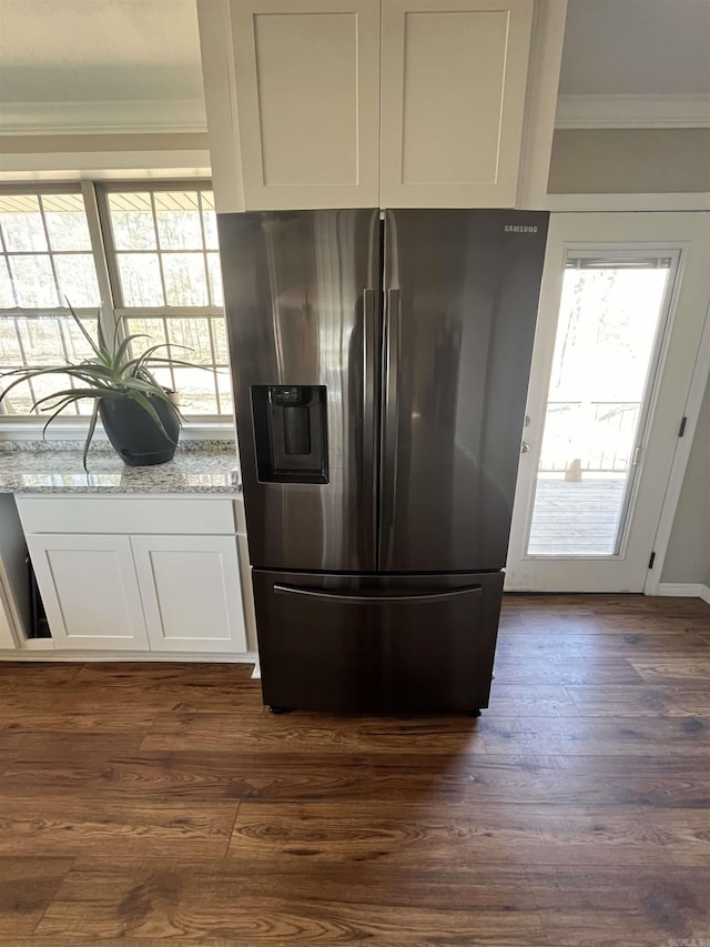 kitchen featuring stainless steel fridge, ornamental molding, light stone counters, dark wood-style flooring, and white cabinetry